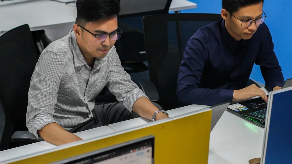 Personas trabajando con computadoras en una oficina.